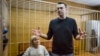 Russian opposition leader Alexei Navalny gestures while speaking, as his lawyer Olga Mikhailova listens, in court in Moscow, Russia, March 27, 2017. 