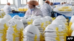 Foto de 28 de fevereiro 2020 de trabalhadores numa fábrica de máscara faciais em Handan, China