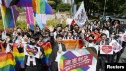 People including plaintiffs' lawyers hold banners and flags after the lower court ruled that not allowing same-sex marriage was unconstitutional outside Nagoya district court