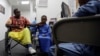 FILE - Ali Said, of Somalia, left, waits at a center for refugees with his two sons, July 6, 2017, in San Diego. Said, whose leg was blown off by a grenade, says he felt unbelievably lucky to be among the last refugees allowed into the United States before stricter rules kicked in as part of the Trump administration's travel ban.