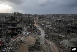 Warga Palestina berjalan di tengah bangunan yang hancur akibat serangan udara dan darat Israel di Jabaliya, Jalur Gaza, 6 Februari 2025.