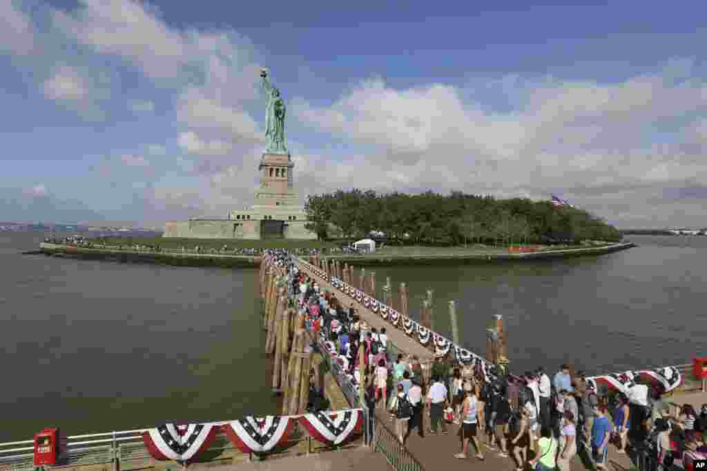 Visitors to the Statue of Liberty disembark onto Liberty Island from the first ferry to leave Manhattan, July 4, 2013.