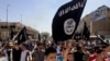 File - Demonstrators chant pro-Islamic State group slogans as they wave the group's flags in front of the provincial government headquarters in Mosul, Iraq, June 2014.