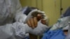 Un trabajador de la salud toma la mano de un paciente con COVID-19 en la unidad de cuidados intensivos del Hospital público Ana Francisca Pérez de León II en Caracas, Venezuela. Marzo 28, 2021.