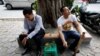 FILE - A man smokes from a bamboo pipe as another holds a cigarette on a street in Hanoi, Vietnam, May 11, 2017.