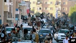 FILE - Fighters from the Islamic State group parade in Raqqa, north Syria, June 30, 2014. 