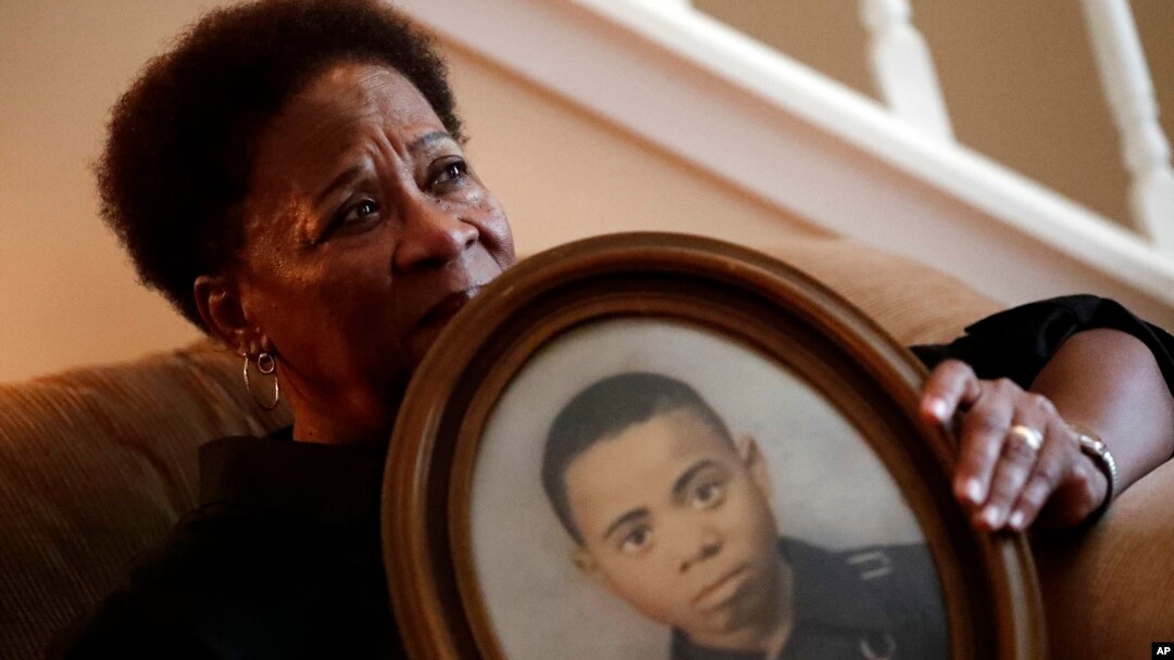 In this Aug. 9, 2018 photo, Eberlene King poses with a photograph of her brother William Roy Prather when he was about 15 years old at her home in Doraville, Georgia.