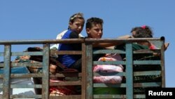 Anak-anak menaiki sebuah truk bersama barang bawaan di Deraa, Suriah, 22 Juni 2018.