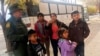 FILE - A migrant family from Central America waits outside the Annunciation House shelter in El Paso, Texas, after a U.S. Immigration and Customs Enforcement officer drops them off, Nov. 29, 2018. 