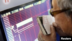 Seorang investor memperhatikan layar yang menunjukkan informasi saham, setelah mekanisme "circuit breaker" menangguhkan perdagangan saham, di Shanghai, China, 7 Januari 2016. 