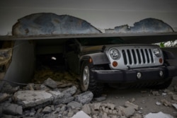A car is crushed under a home that collapsed after the previous day's magnitude 6.4 earthquake in Yauco, Puerto Rico, Jan. 8, 2020. More than 250,000 Puerto Ricans remained without water and another half a million without electricity.