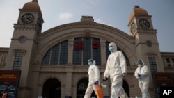 资料照：2020年4月7日，在中国湖北省武汉市恢复出境交通前夕，身穿防护服的人员走过汉口火车站。 