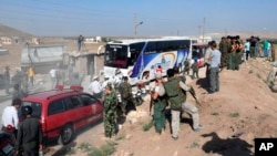 This photo released by the Syrian official news agency SANA, shows Syrian troops, journalists and civilians watching as buses evacuate people from the two pro-government villages of Foua and Kfarya, at Tel el-Eis, the crossing between Aleppo and Idlib provinces, Syria, July 19, 2018. 