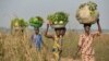 FILE - Women come back from the fields to sell vegetables at a market near the internally displacement camp close to the airport in Bangui.