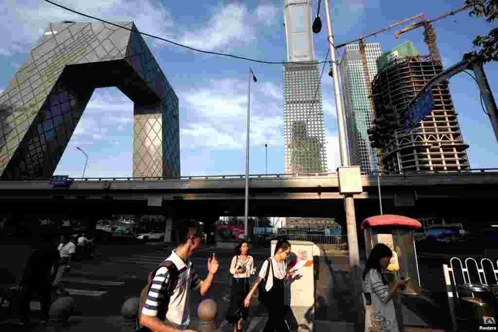 人们走近北京中央商务区的中央电视台(CCTV)大楼附近(2018年8月16日)。 8月22日,中国教育部通知全国各地的学校,要学生和家长在9月1日晚上8点一起观看教育部和中央广播电视总台联合制作的节目《开学第一课》。 一些地方学校当局还要求学生家长“发一张孩子与家人一起观看节目的照片分享到班级群” 。但观众先看到的是将近15分钟的连续广告, 有推广培训机构的,有宣传学习APP 的。有人说这是广告第一课。有人写道:“ 是该骂!第一不守时,第二强制观看,第三一边喊着减负,一边大力做培训广告?我想说这是来搞笑的吗? ”
