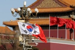 FILE - South Korea and China's flags flutter next to Tiananmen Gate during the visit of South Korean President Moon Jae-In in Beijing, China, Dec. 15, 2017.