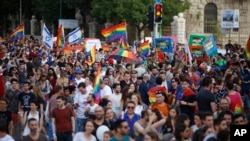 Participants wave flags and hold signs during the annual Gay Pride parade in Jerusalem, June 6, 2019.