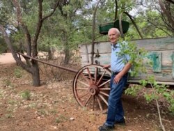Forrest Fenn stands in front of an original 19th century cart he had placed on the old Santa Fe trail running through his property. (VOA/Penelope Poulou)