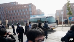 Journalists and security personnel gather near the entrance of the Wuhan Institute of Virology after a visit by the World Health Organization team in Wuhan in China's Hubei province on Feb. 3, 2021.