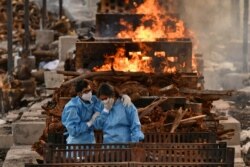 Anggota keluarga Vijay Raju, yang meninggal karena COVID-19, berkabung sebelum dikremasi di tempat krematorium di desa Giddenahalli di pinggiran Bengaluru, India, 13 Mei 2021. (Foto: Reuters)