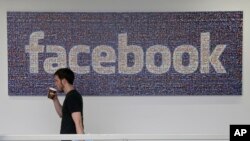 Seorang pegawai Facebook berjalan melewati logo perusahaan di markas besar Facebook di Menlo Park, California.
