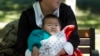 A child is wrapped up against the cold at a park in Beijing, China, Oct. 30, 2015. Shares of companies making diapers, baby strollers and infant formula got a boost Friday from China's decision to scrap its one-child policy.