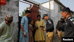Pokiston politsiyasi afg'on qochoqlarining hujjatini tekshirmoqda, Karachi, Pokiston, 2023-yil, 21-noyabr.