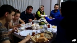 On the first day of the Muslim holy month of Ramadan, Selami Aykut, 38, center, and his family observe the sahoor traditional breakfast of Ramadan, in Istanbul, after being woken by street drummers early Monday, June 6, 2016. 