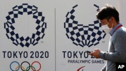 東京一名男子走過東京奧運會和殘奧會的標誌。(2021年2月1日)