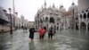 Orang-orang mengarungi banjir yang mengepung Lapangan Santo Markus di Venesia, Italia, 13 November 2019.