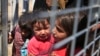 A Syrian child carries a baby crying while they wait with others to cross back to the border town of Tal Abyad in Syria from Turkey, at the border crossing in Akcakale, southeastern Turkey, June 17, 2015. 