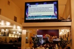 FILE - A tweet by U.S. President Donald Trump about the coronavirus is seen on a Chinese TV broadcast inside a restaurant in the Chinatown section of San Francisco, California, Feb. 24, 2020. Trump tweeted before markets fell due to virus fears.