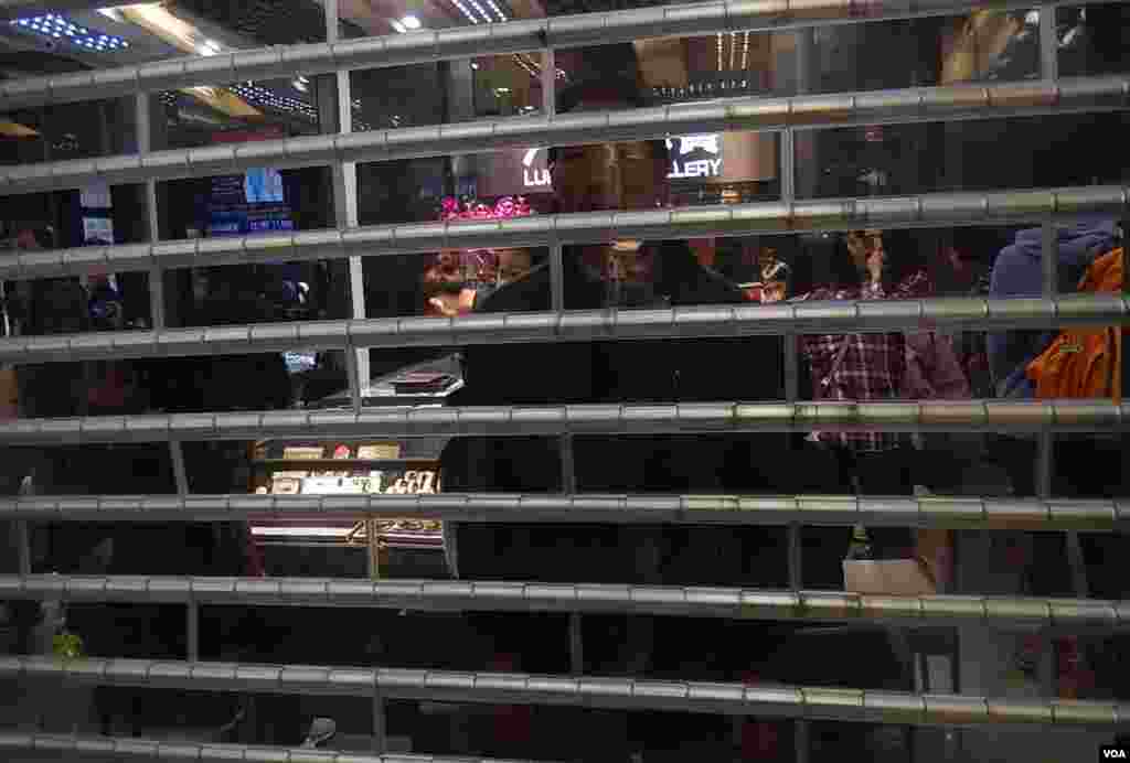 商場內部份商店落閘,有中國遊客隔著透明閘門觀察示威情況。(美國之音湯惠芸攝)