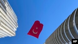 A Turkish flag suspended between two skyscrapers flutters in the wind, in Istanbul, April 23, 2020, to mark centennial celebrations for the founding of Turkey's parliament.