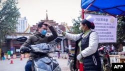 A Myanmar health officer checks the temperature of a motorist entering the Myanmar-China border crossing checkpoint in Muse, Shan State on January 31, 2020.