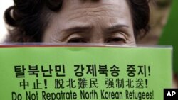 一名婦人去年在南韓首爾的中國領事館前持標語牌抗議中國遣返“脫北者”。(資料圖片)