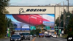 FILE - Traffic passes in view of a massive Boeing airplane production plant, Oct. 1, 2020, in Everett, Wash.