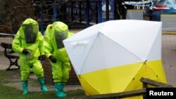 The forensic tent, covering the bench where Sergei Skripal and his daughter Yulia were found, is repositioned by officials in protective suits in the center of Salisbury, Britain, March 8, 2018.