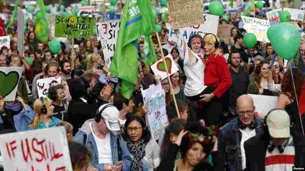 People hold banners and dance during a Climate Change March demanding politicians take tougher action to protect the climate, in Berlin, Sept. 21, 2014.