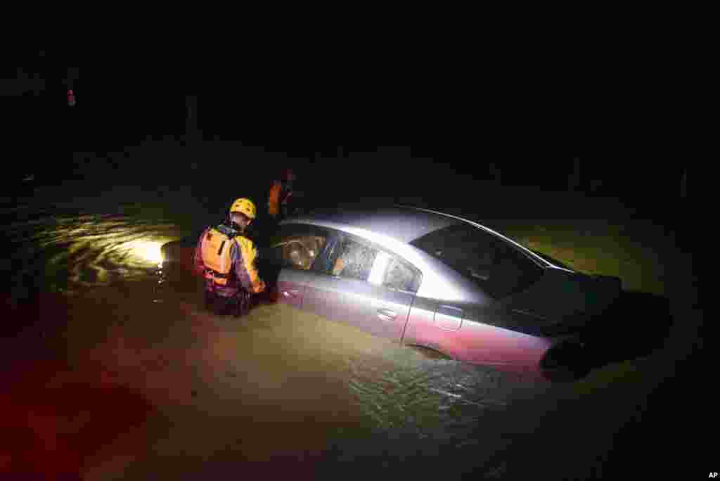 Rescue staff from the Municipal Emergency Management Agency investigate an empty flooded car during the passage of Hurricane Irma through the northeastern part of the island in Fajardo, Puerto Rico, Sept. 6, 2017.