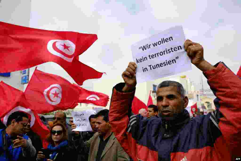 Warga Tunisia melambaikan bendera pada sebuah demonstrasi di Midoun, sebelah barat laut Djerba, dua hari setelah pria-pria bersenjata menyerang Museum Nasional Bardo. Serangan tersebut menewaskan 21 orang, aksi kekerasan terparah di negara ini sejak penggulingan pemimpin Tunisia Zine El Abidine Ben Ali pada tahun 2011.
